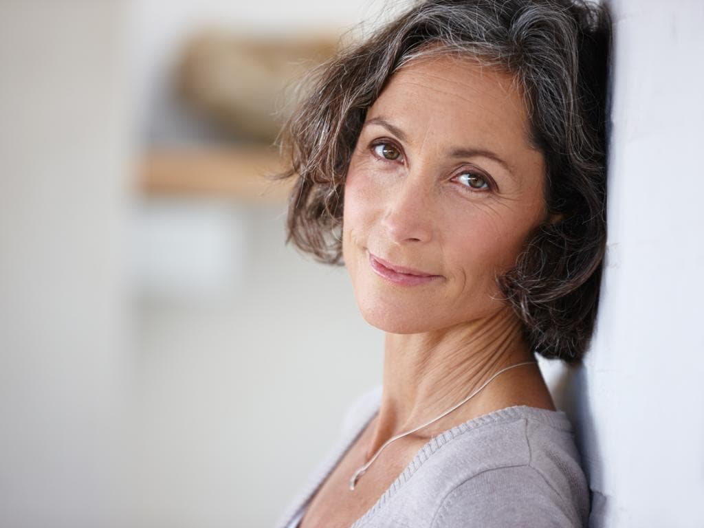 Person with back against wall smiling L