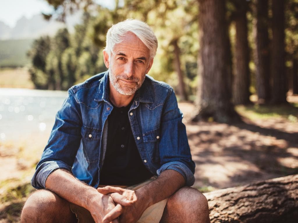 Elderly man sitting by a lake and forest L