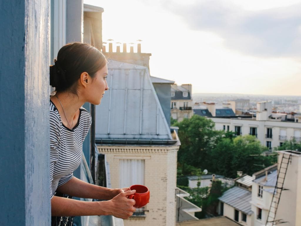 Person looking out of window in apartment building L